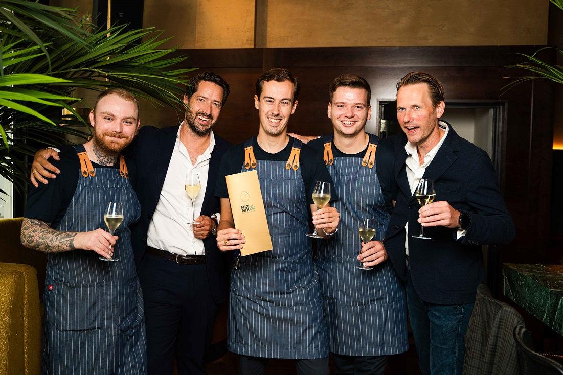 Groep mannen in horeca, sommigen in schort, proosten met alcoholvrije wijn in restaurant | World of NIX