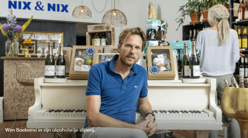 Man zit voor een witte piano met alcoholvrije drankcadeaus in een moderne slijterij | World of NIX