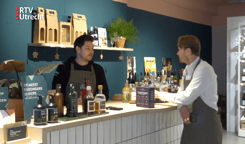 Twee mannen aan een bar met alcoholvrije spirits en wijnen in moderne winkelsetting | World of NIX