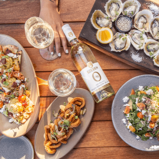 Alcoholvrije Sauvignon Blanc, zeevruchten, salade en fingerfood op houten tafel | World of NIX