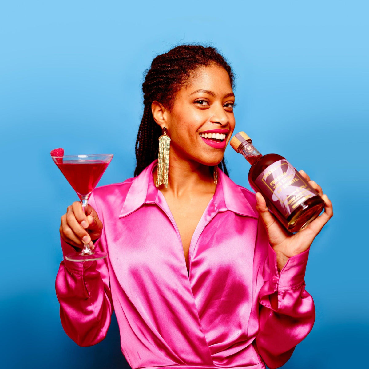 Vrouw in roze blouse met alcoholvrije cocktail en fles, blauwe achtergrond | World of NIX