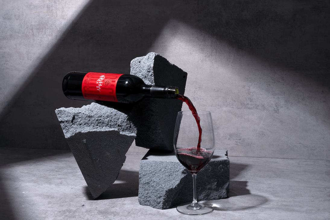 Fles rode alcoholvrije wijn wordt in wijnglas geschonken op betonnen blokken | World of NIX