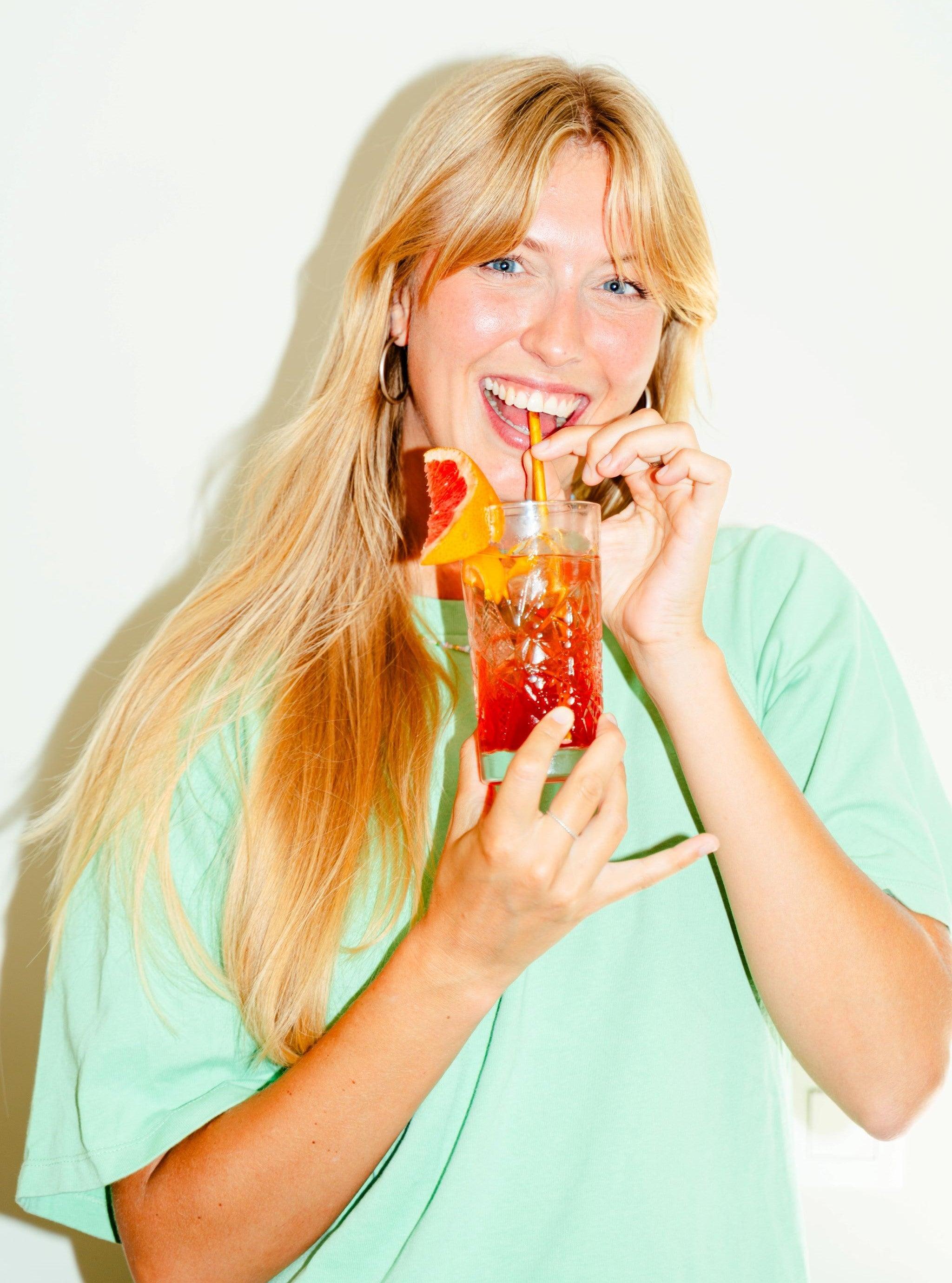 Vrouw met lang blond haar drinkt een alcoholvrije cocktail met citrus en ijs | World of NIX