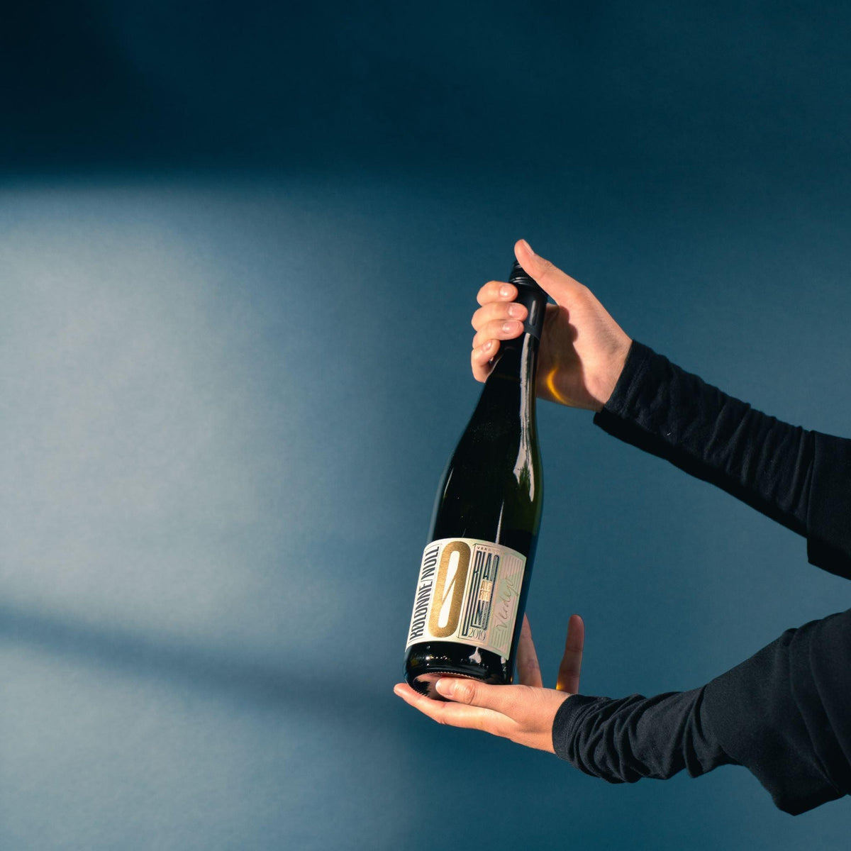 Fles alcoholvrije Verdejo wijn in handen, blauwe achtergrond | World of NIX
