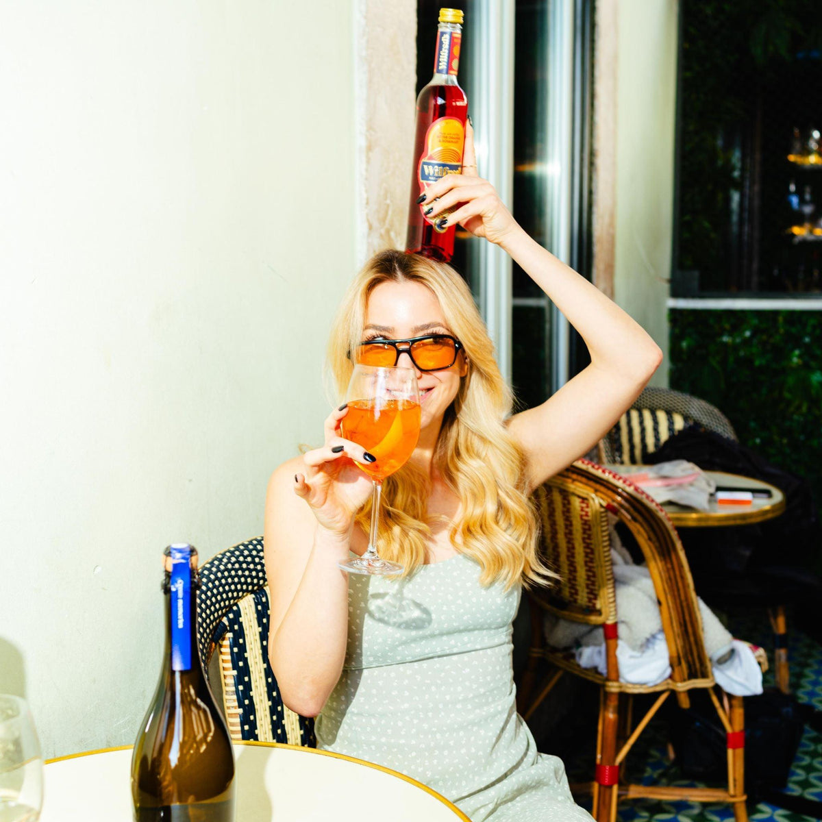 Vrouw met oranje zonnebril drinkt alcoholvrije oranje drank op terras | World of NIX