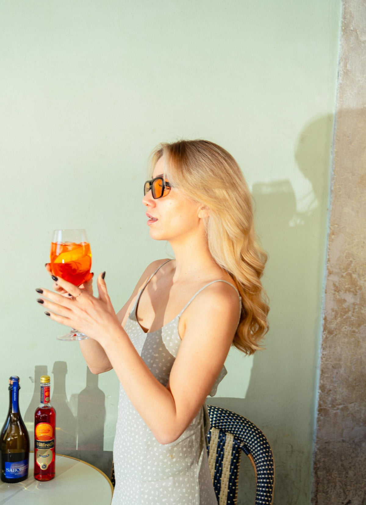 Vrouw met zonnebril geniet van zomercocktail op terras met alcoholvrije dranken | World of NIX