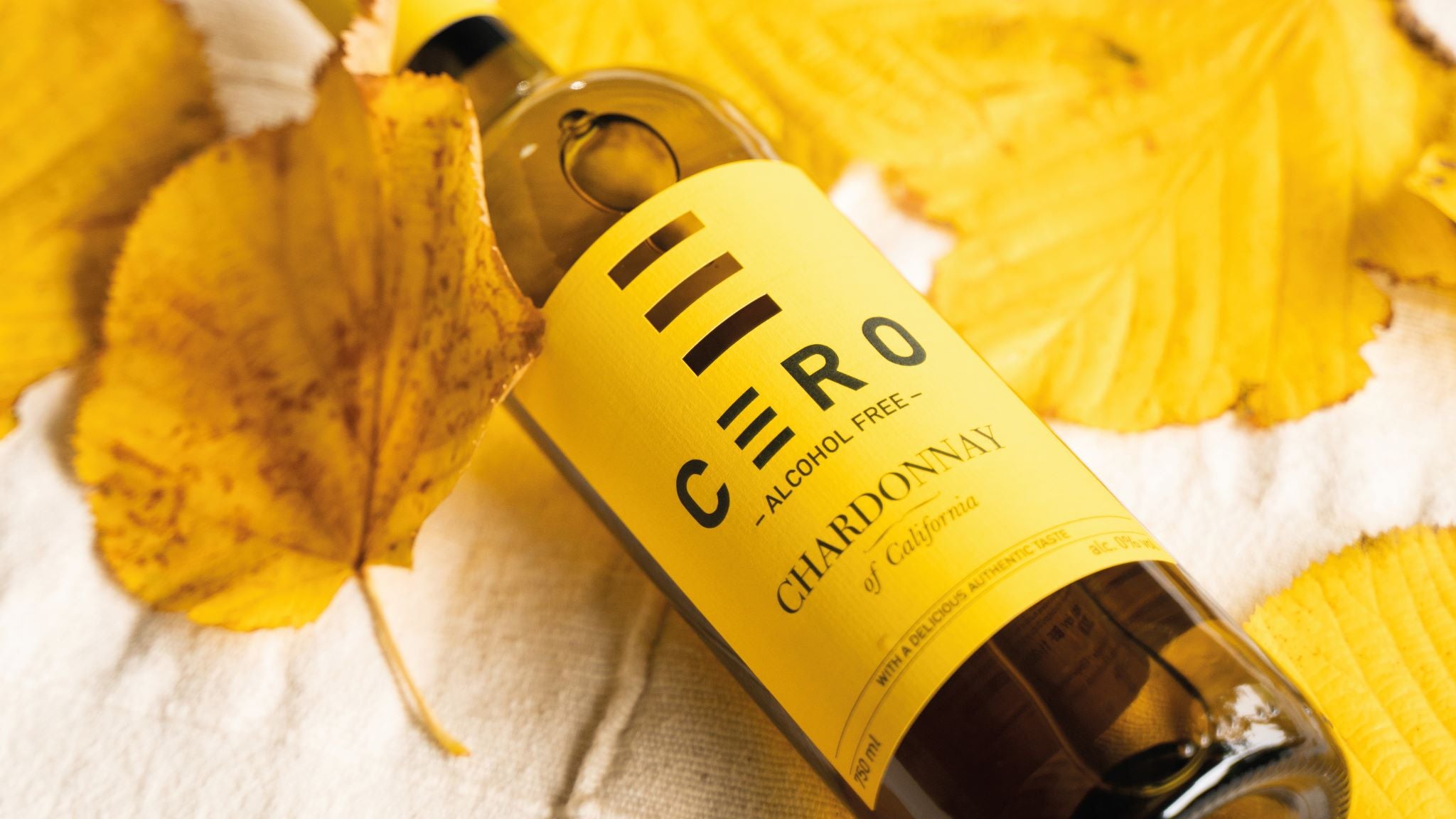 De fles alcoholvrije Chardonnay van Cero met bijpassende kleuren blaadjes bedekt.