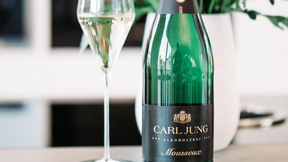 Alcoholvrije bubbel van Carl Jung in een mooi champagne glas met de fles ernaast.