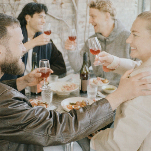 Vrienden proosten met alcoholvrije wijn aan tafel bij World of NIX, vrolijke sfeer, eten