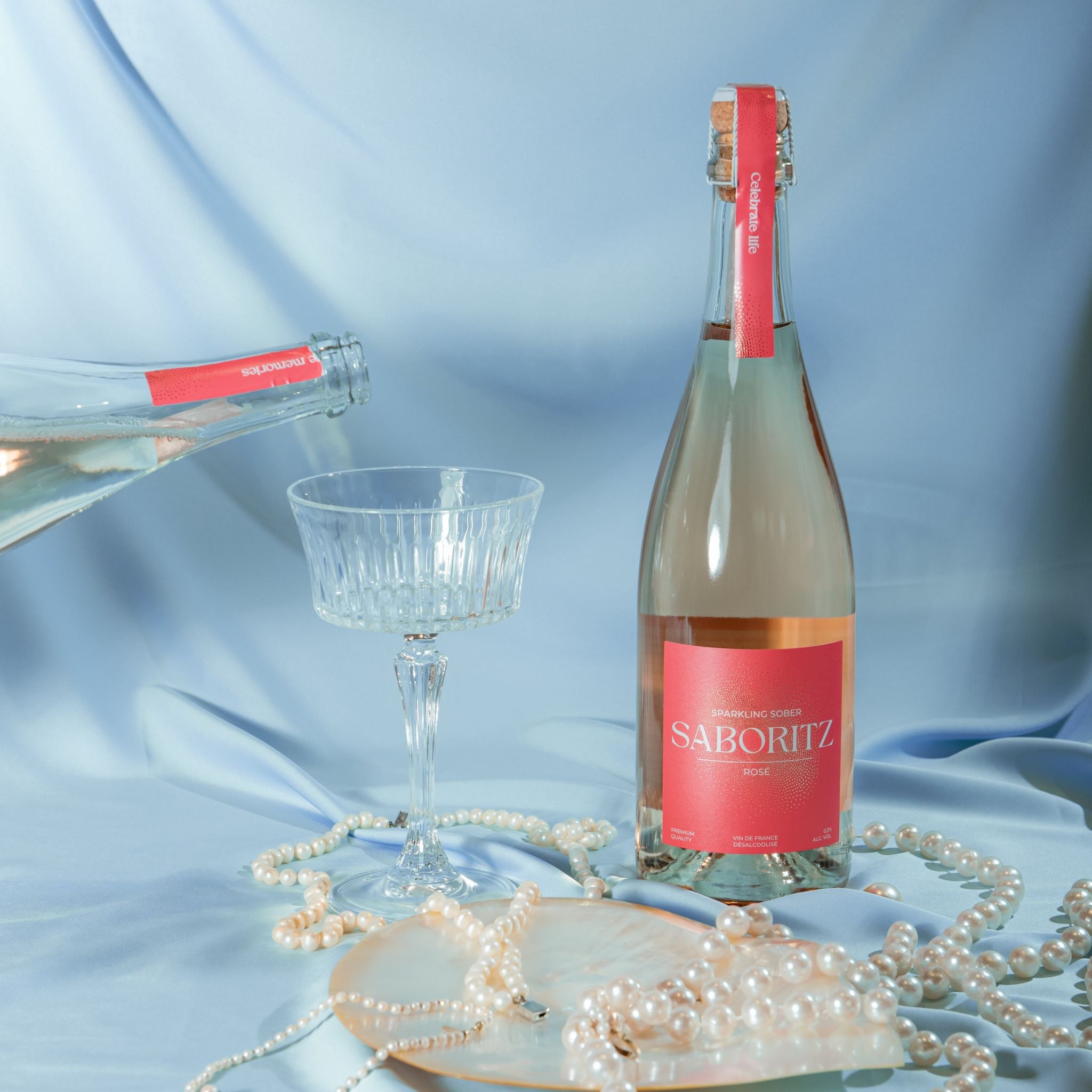 Saboritz rosé alcoholvrije sparkling wijn op blauwe zijden achtergrond met parels en glas bij World of Nix