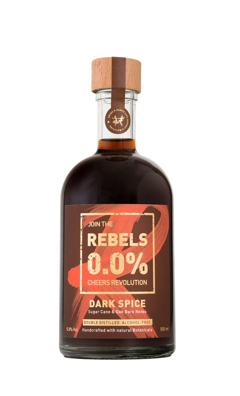 Een fles met donkere vloeistof en een etiket waarop 'REBELS 0.0% Dark Spice' staat, afgesloten met een houten dop en een cirkelvormig logo bovenaan.