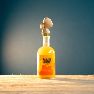 De gemberdrank van Paulies Ginger mooi gepresenteerd met een stuk gember bovenop de fles.
