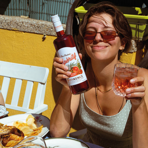 Vrouw geniet van alcoholvrije aperitief Abstinence met chips op zonnig terras, World of NIX