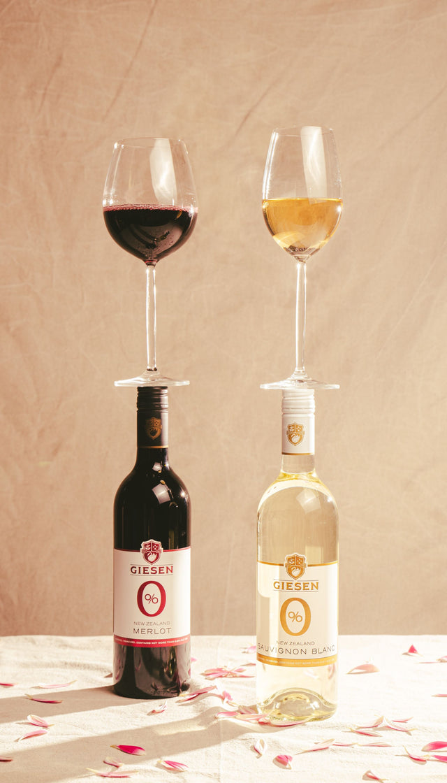 De flessen Giesen Merlot en Sauvignon Blanc mooi gepresenteerd met een gevuld glas wijn.