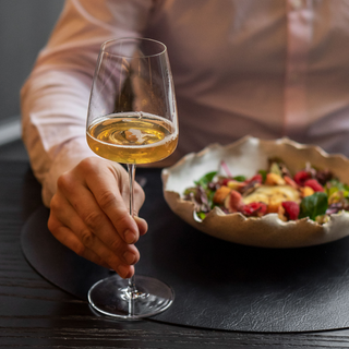 Een elegante tafelsetting met een geopende fles Acala White Wine Style mousserende thee, uitnodigend voor een gastronomische ervaring.