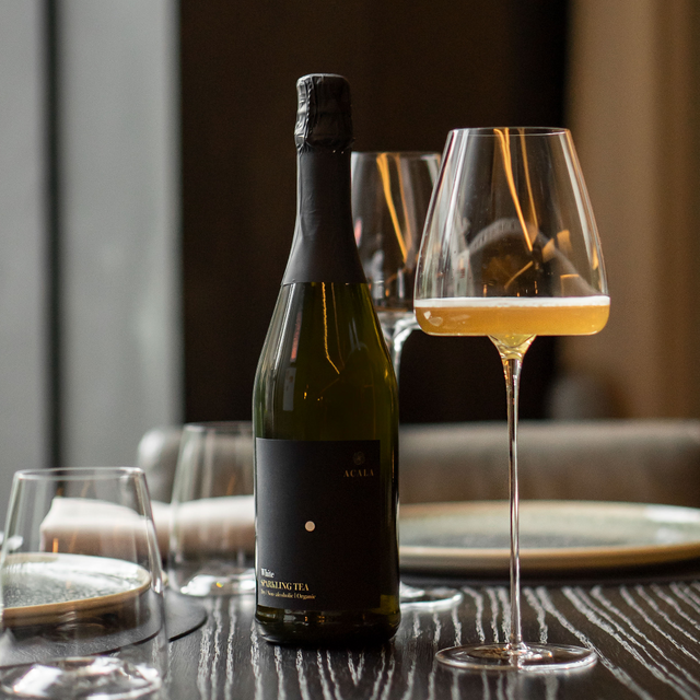 Twee glazen met Acala Sparkling Tea White Wine Style op een elegante tafelsetting