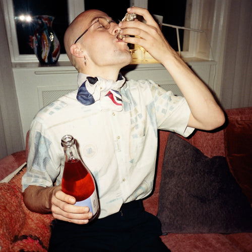 Man drinkt alcoholvrije drank op bank met World of Nix sparkling tea, huiselijke sfeer