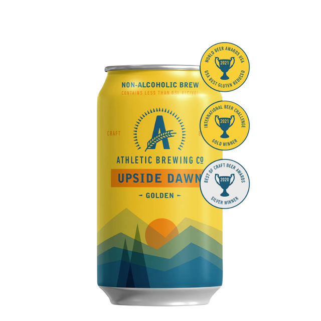 Een geel blikje Athletic Brewing's 'Upside Dawn' non-alcoholische Golden Ale met een design dat landschapselementen toont en omringd door gouden award-stickers.